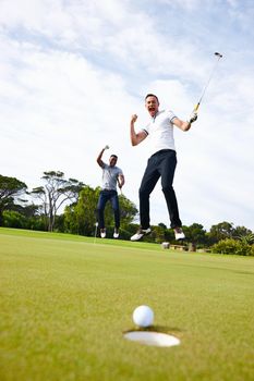 How could golf ever be boring. Low angle shot of a golf ball approaching the hole while two golfers look on.