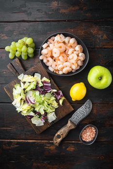 Seafood salad or appetizer shrimp and other ingredients, with sauce apple and grape, on old dark wooden table , top view flat lay