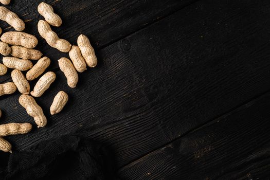 Organic peanuts in shell, on black wooden table background, top view flat lay, with copy space for text