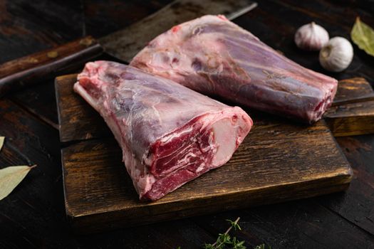 Raw lamb shanks with ingredients, on old dark wooden table background