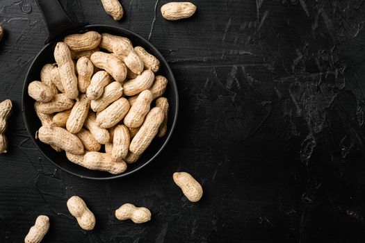 Organic peanuts in shell, on black dark stone table background, top view flat lay, with copy space for text