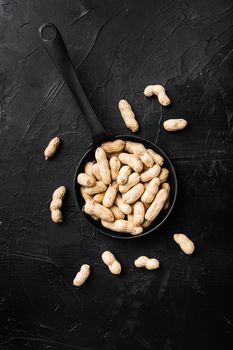 Whole peanut nuts, on black dark stone table background, top view flat lay