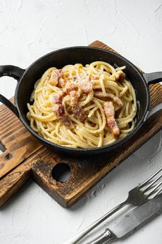 Classic Homemade Pasta carbonara Italian with Bacon, eggs, Parmesan Cheese, in cast iron frying pan, on white stone surface