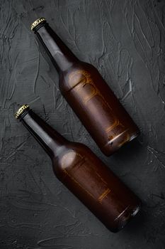 Fresh beer in glass bottles, on black stone background, top view flat lay