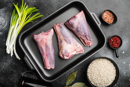 Raw lamb shanks meat, on black dark stone table background, top view flat lay