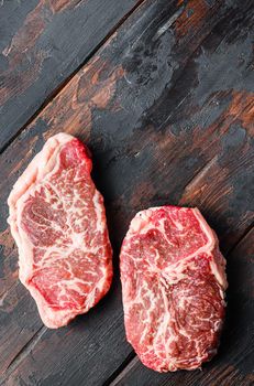 Top blade organic meat cut, raw marbled beef steak, On dark wooden background, top view with space for text.