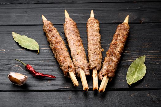 Mutton kebab shish skewers, on black wooden table background