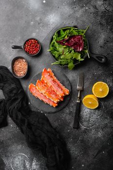 Fresh frozen organic crab legs, on black dark stone table background, top view flat lay, with copy space for text