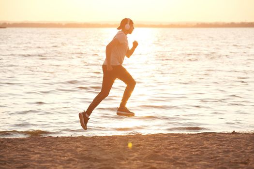 man in sports clothes running on the evening beach .
