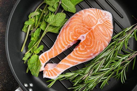 Raw salmon fish fillet with fresh herbs, in cast iron frying pan, top view flat lay