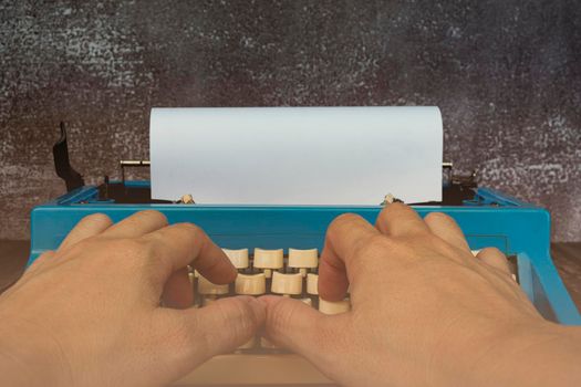 Businessman hands typing on an old typewriter on wooden desk.