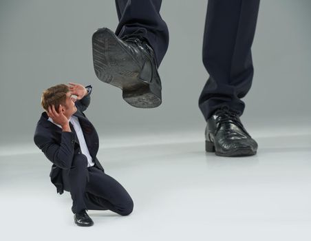Trampled by The Man. Cropped view of a businessman crouched as a giant shoe comes down on him.