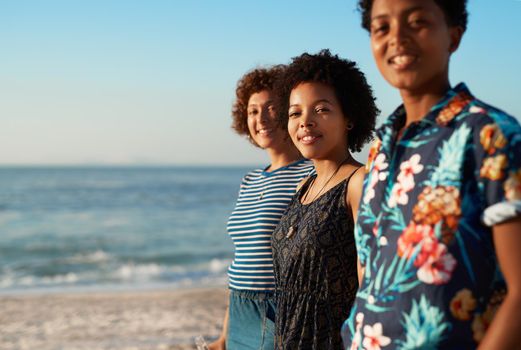 Were in this life together. Portrait of an attractive young trio of women standing together and posing on the beach during the day.
