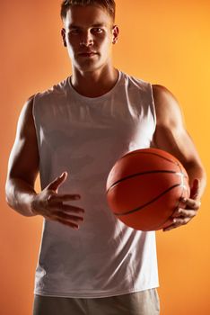 Basketball is my game. Studio portrait of a handsome young male basketball player posing against an orange background.