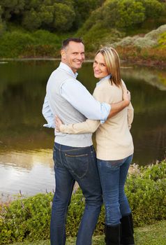 They both enjoy the tranquility of the water. Portrait of a loving mature couple standing near a lake.