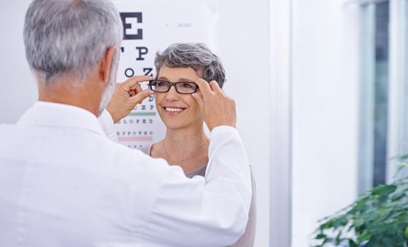 This pair is perfect for you. Shot of an optometrist putting a pair of glasses on a patient.