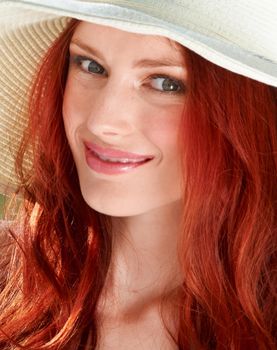 Fiery summer. A young redheade woman wearing a sunhat.