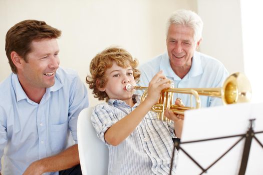 Musical talent runs in this family. Shot of a cute little boy playing the trumpet while his father and grandfather watch him proudly.