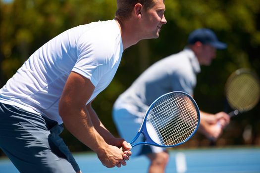 Team tennis. Shot of two men playing a tennis match on a sunny day.