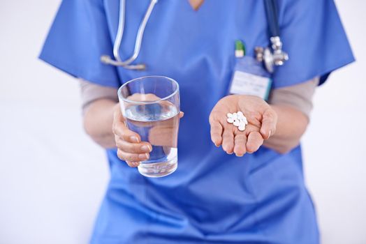 Heres your medication for the week. Shot of a female doctor holding medication and glass of water.
