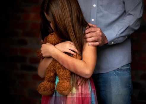 Innocence lost. Abused little girl with her abuser gripping her shoulder.