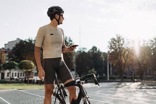 Cyclist holding smartphone while sitting on black bike