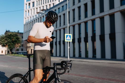 Muscular man using smartphone after cycling on street