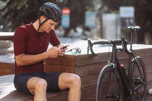 Cyclist surfing internet on mobile while resting outdoors