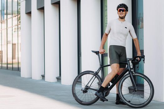 Cyclist in activewear standing outdoors with bike
