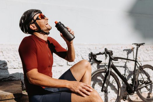 Happy cyclist drinking water after outdoors activity