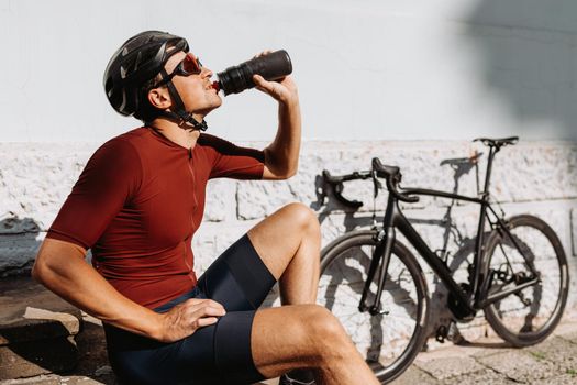 Cyclist in sportswear drinking water after ride outdoors