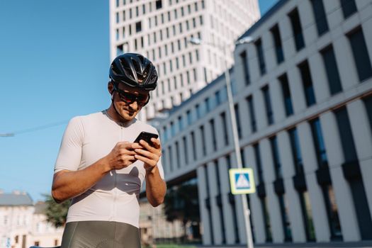 Cyclist standing on city street and using smartphone