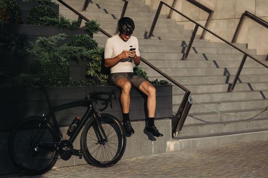 Man texting on mobile while sitting on street near bike