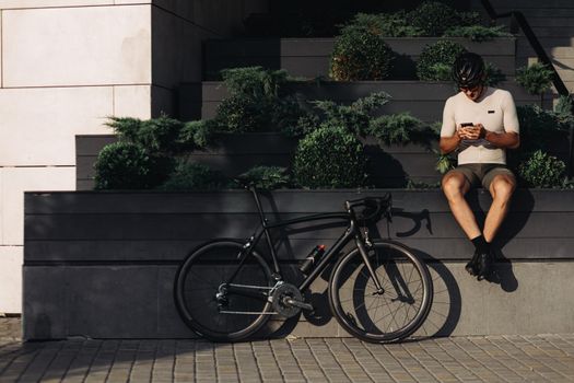 Sportsman in activewear using cell phone after cycling