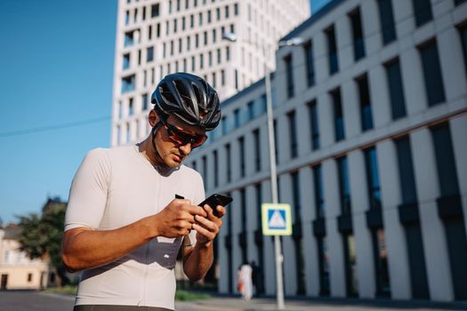 Cyclist using mobile while resting after workout on street