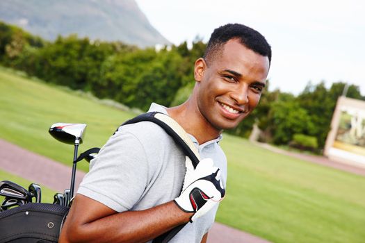 Ready to get on the green. Portrait of a handsome young man standing on a golf course with his bag of clubs.