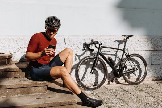 Cyclist using mobile while resting after ride