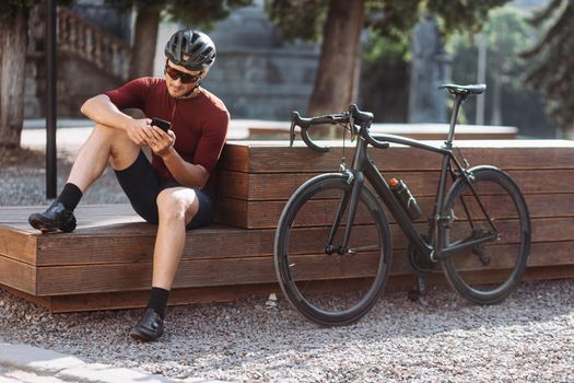 Cyclist in activewear using smartphone while resting