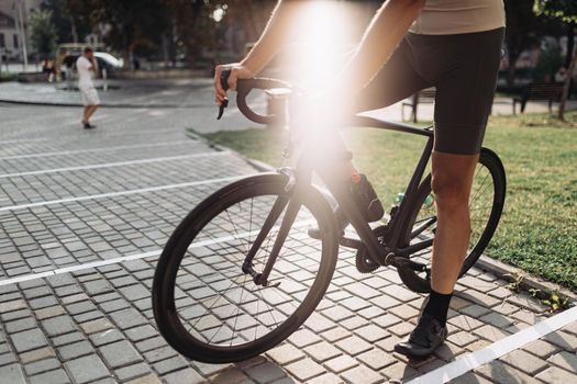 Cyclist in activewear sitting on black bike outdoors