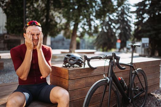 Exhausted man touching face while resting after cycling