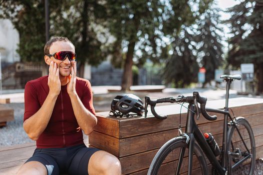 Positive cyclist resting on wooden bench outdoors