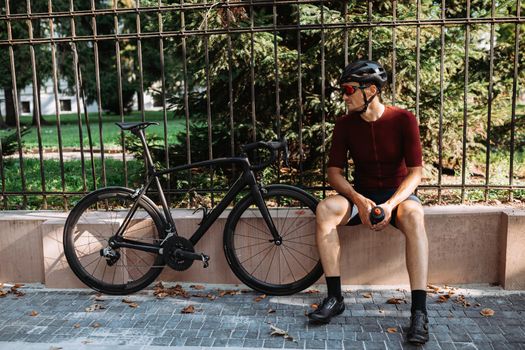 Cyclist in helmet and glasses resting outdoors after workout