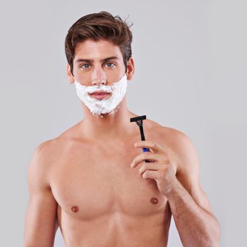 The basic tool of mens care. Studio shot of a handsome bare chested young man shaving.
