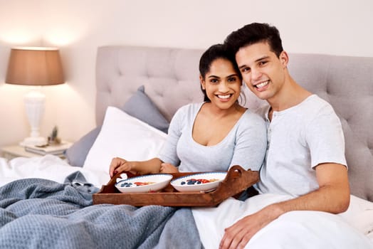 Start your day with love and a good meal. Shot of a happy young couple having breakfast in bed together.