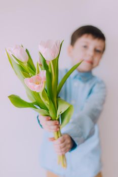 A boy with a bouquet of tulips lifestyle . Postcard for March 8. Congratulations on Women's Day. Congratulations on Mother's Day. Flowers are tulips.