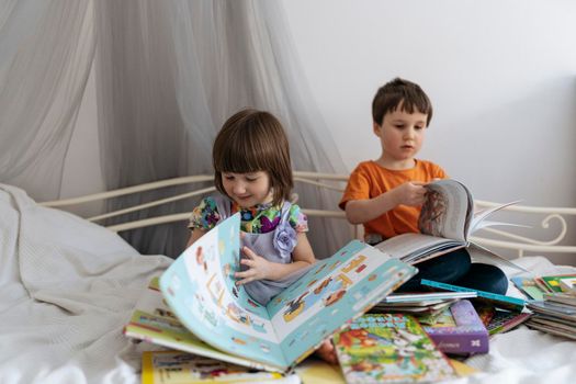 Two siblings reading books on the sofa