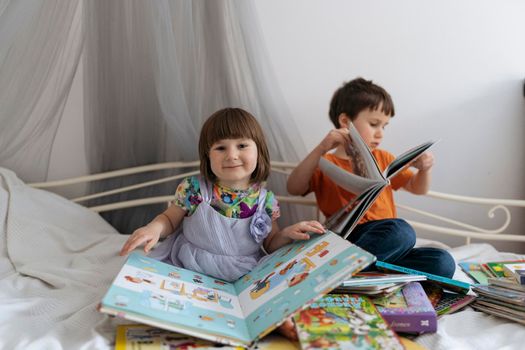 Two siblings reading books on the sofa