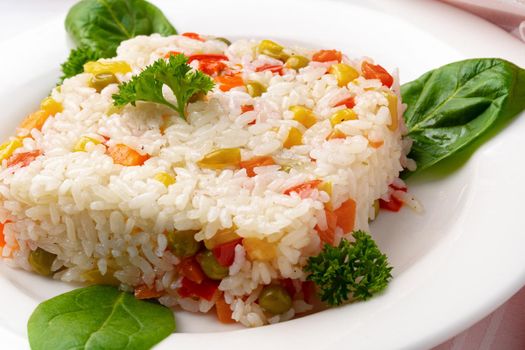 Cooked white rice mixed with colorful vegetables on white plate