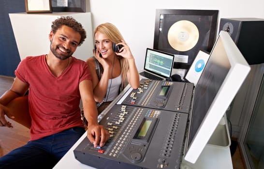 Ready to take the recording industry by storm. Two young sound engineers sitting in their recording studio smiling at the camera.