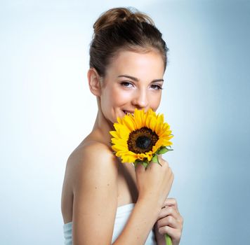 Double the beauty. Studio portrait of a beautiful young woman holding a sunflower.